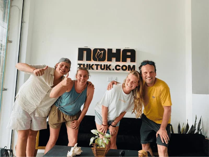 Travellers smiling in front of the NOHA TUKTUK sign at the Galle office