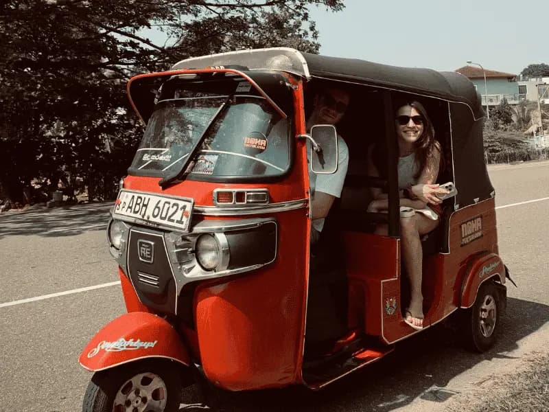 A traveller in the back of a red NOHA self-drive tuk tuk at handover in Galle