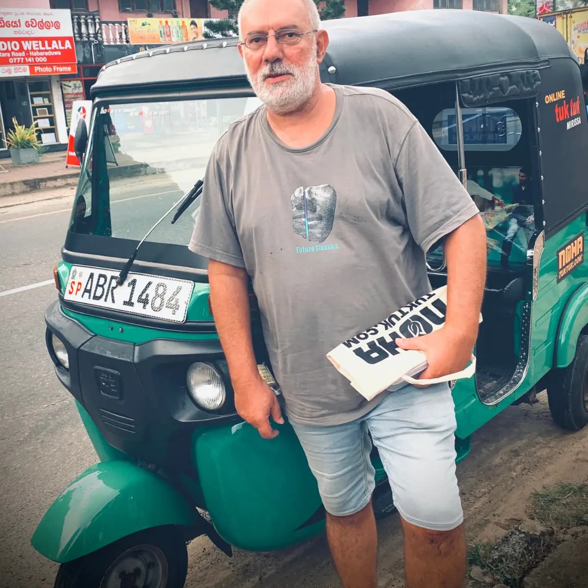 A NOHA customer holding their driving-permit paperwork beside a rented tuk tuk in Sri Lanka