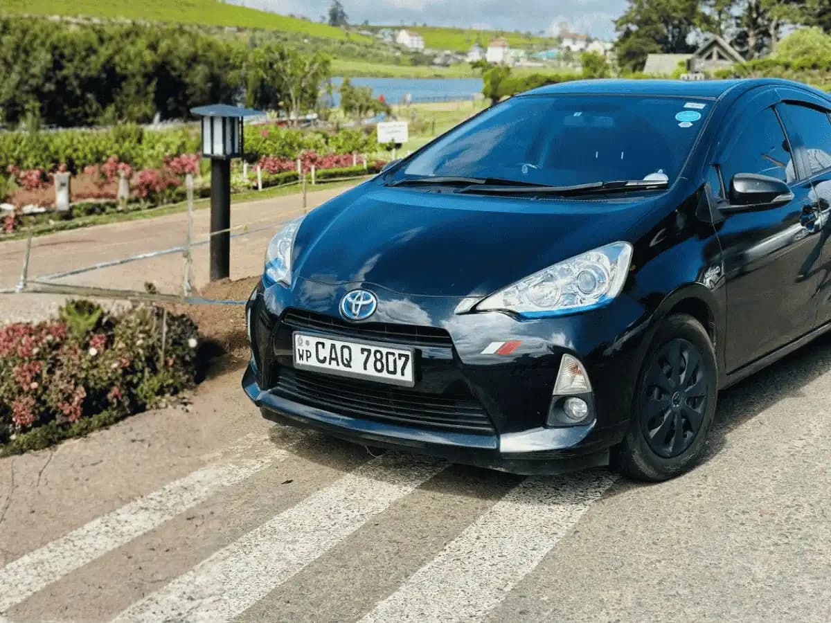 Black Toyota Aqua self-drive rental car by a lake in Sri Lanka's hill country