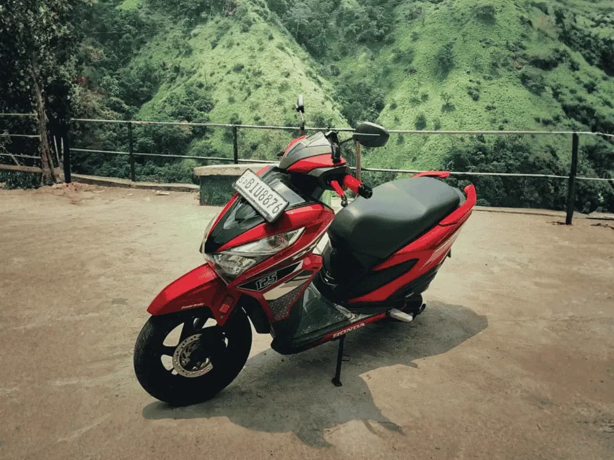 Red Honda Grazia 125 self-drive rental scooter parked at a hill-country viewpoint in Sri Lanka