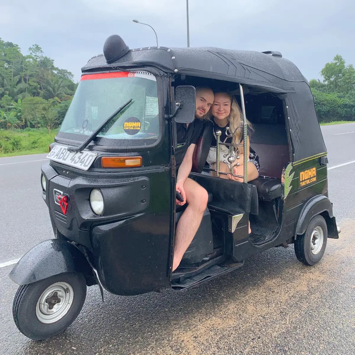Smiling travellers seated inside their NOHA self-drive rental tuk tuk