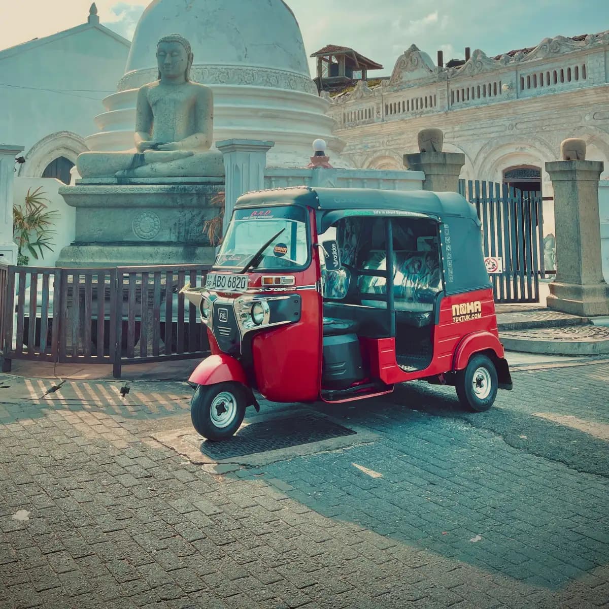 A NOHA rental tuk tuk parked outside a Buddhist temple on Sri Lanka's south coast