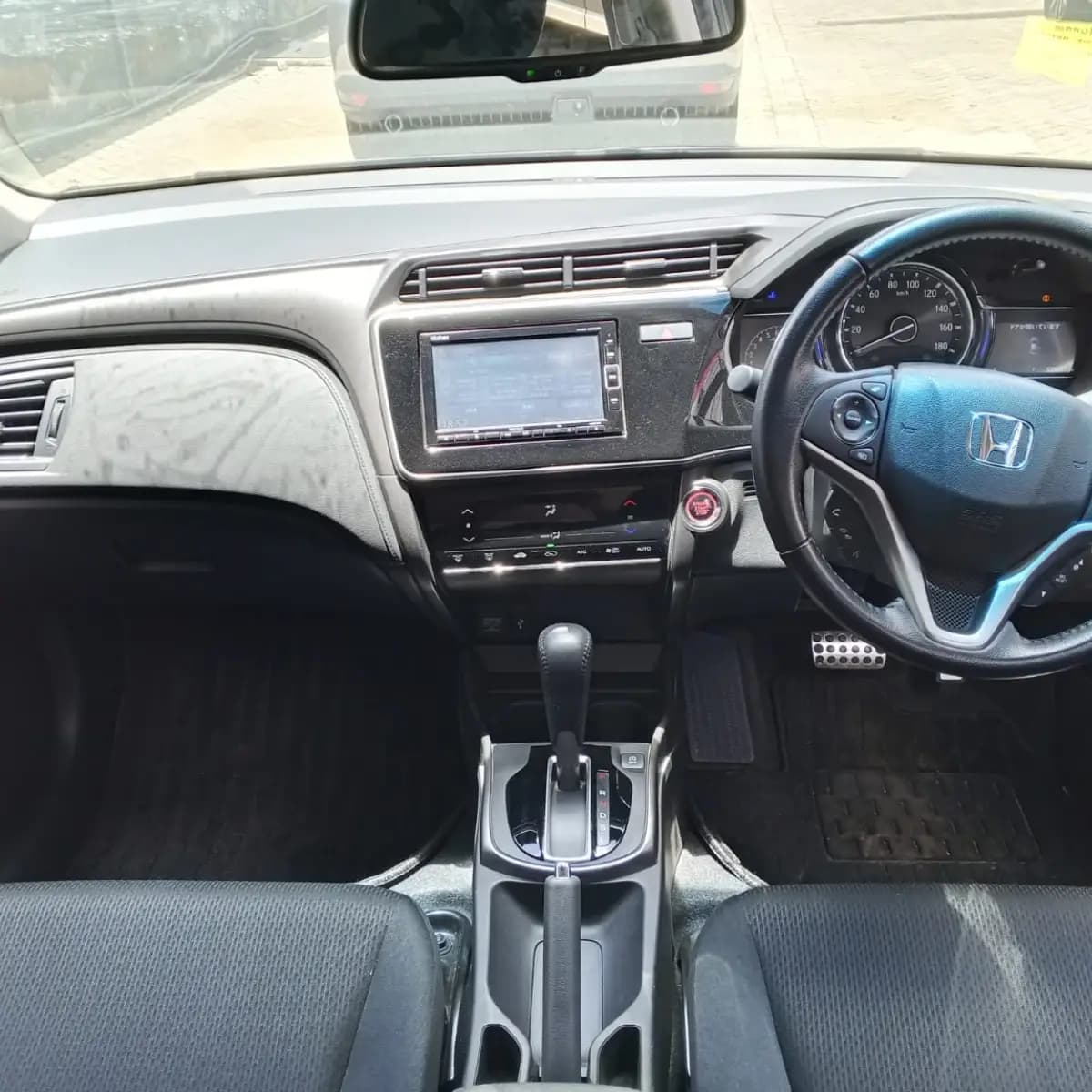 Dashboard, steering wheel and front seats inside a Honda Grace self-drive rental car from NOHA