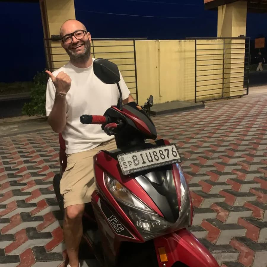 A smiling traveller with their NOHA self-drive rental scooter