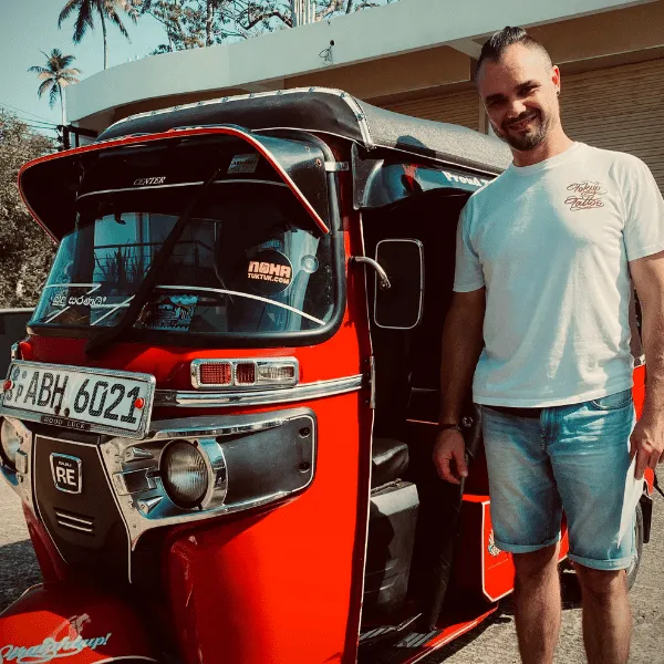 Red Bajaj tuk tuk parked on a Sri Lankan road